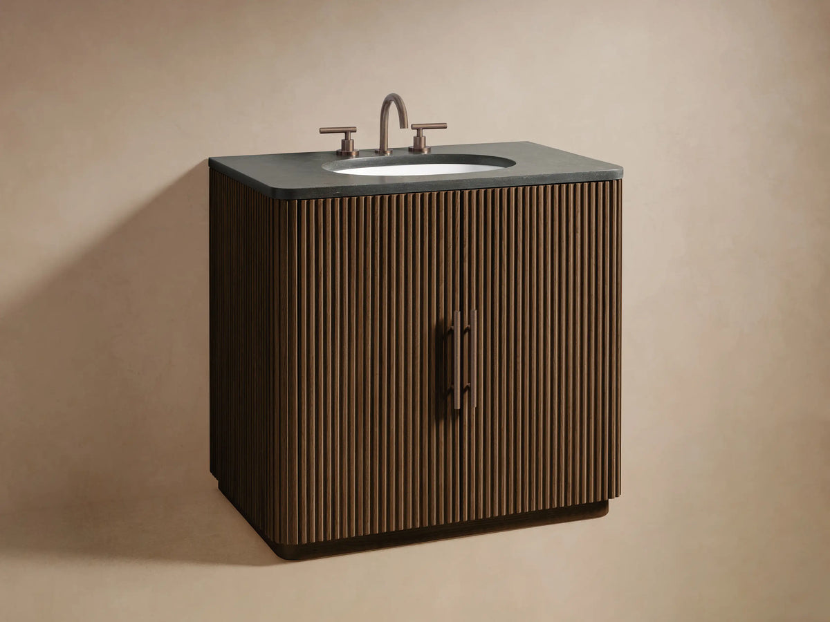Close-up of Finnley Single Vanity's reeded oak door slightly ajar, revealing dark wood interior with shelves, towels, and a wooden bowl.