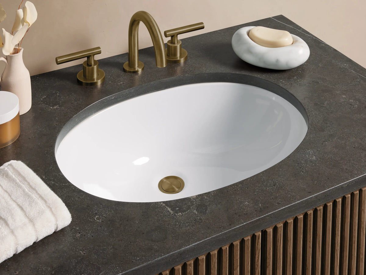 Finnley Single Vanity: front view of dark brown fluted cabinet, dark gray stone top, white oval sink, brass bar handles.