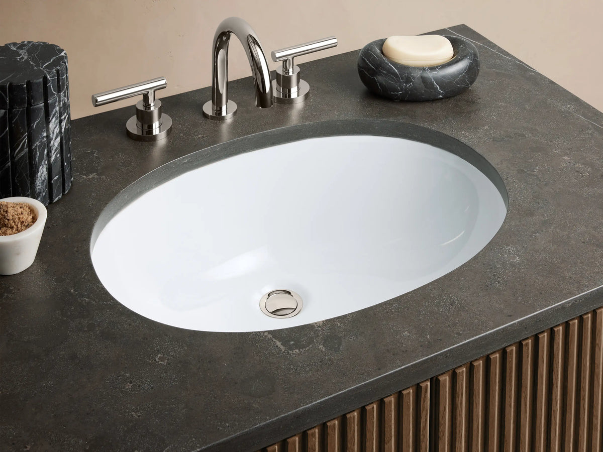 Finnley Single Vanity with ribbed dark wood doors, dark stone top, oval white sink, in a neutral room.