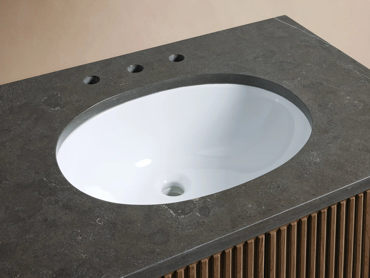Close-up of Finnley Single Vanity. Dark bluestone top, white oval sink, polished nickel faucet, wood-slatted base.