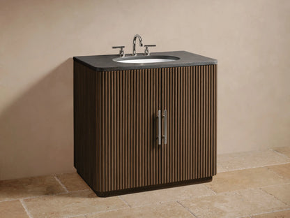 Close-up of Finnley Single Vanity's open, fluted oak cabinet door with polished nickel handle, revealing shelf and towels inside.