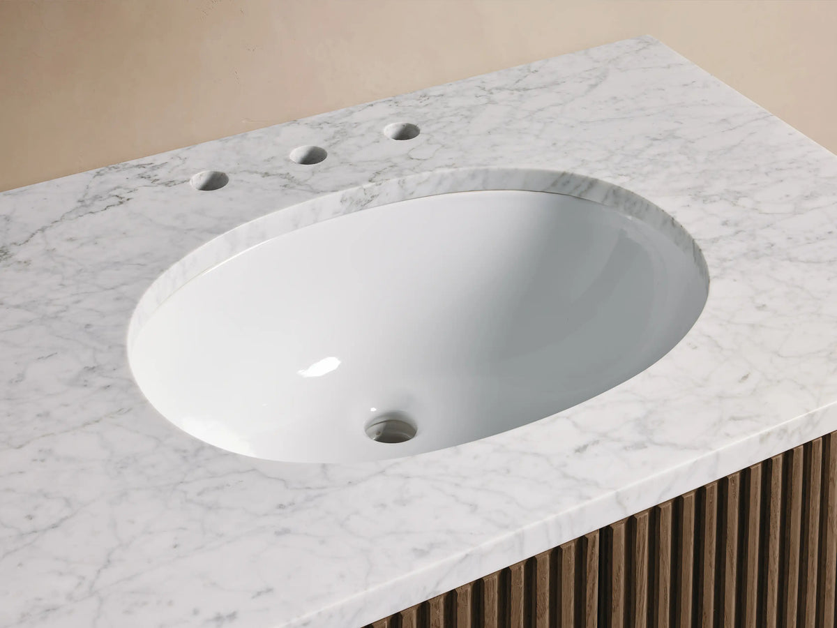 Finnley Single Vanity with white oval undermount sink, Carrara marble countertop, bronze faucet, and slatted wood base.