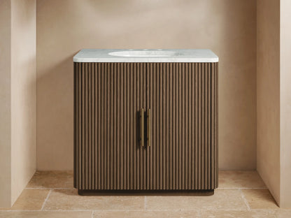 Finnley Single Vanity with dark fluted wood cabinet, white marble top, brass faucet & hardware in a neutral bathroom.