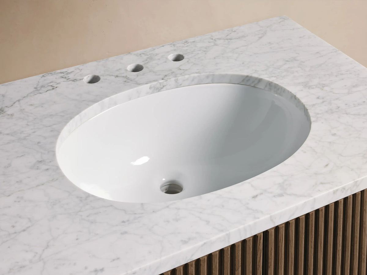 Close-up of Finnley Single Vanity with white oval sink, veined marble top, gold widespread faucet, and textured wood base.