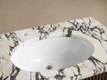 Close-up of Finnley Single Vanity sink and countertop, featuring a white oval sink, veined marble, and antique brass faucet.