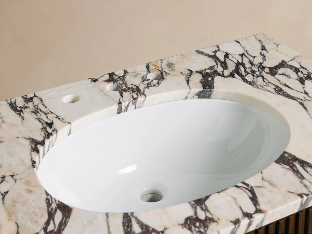 Finnley Single Vanity: oval white sink, chrome widespread faucet, honed Calacatta Viola marble top with brown veining.