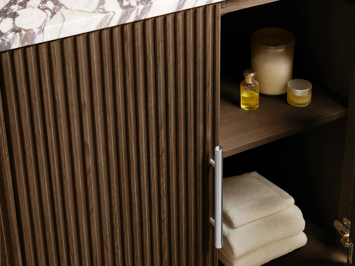 Finnley Single Vanity: Oval white ceramic sink in white marble countertop with black and reddish-brown veins. Three faucet holes.