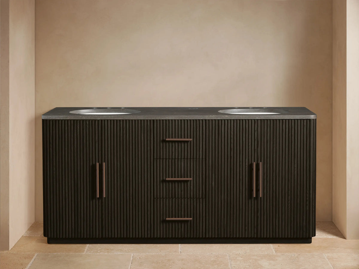 Finnley Wide Vanity: Dark brown fluted double vanity with gray stone top, 2 white sinks, bronze faucets. Left door open, towels visible.