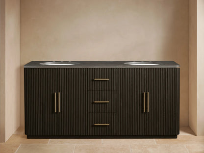 Finnley Wide Vanity, dark brown fluted wood, dark stone top, two oval sinks with brass faucets. Left door open, towels inside.