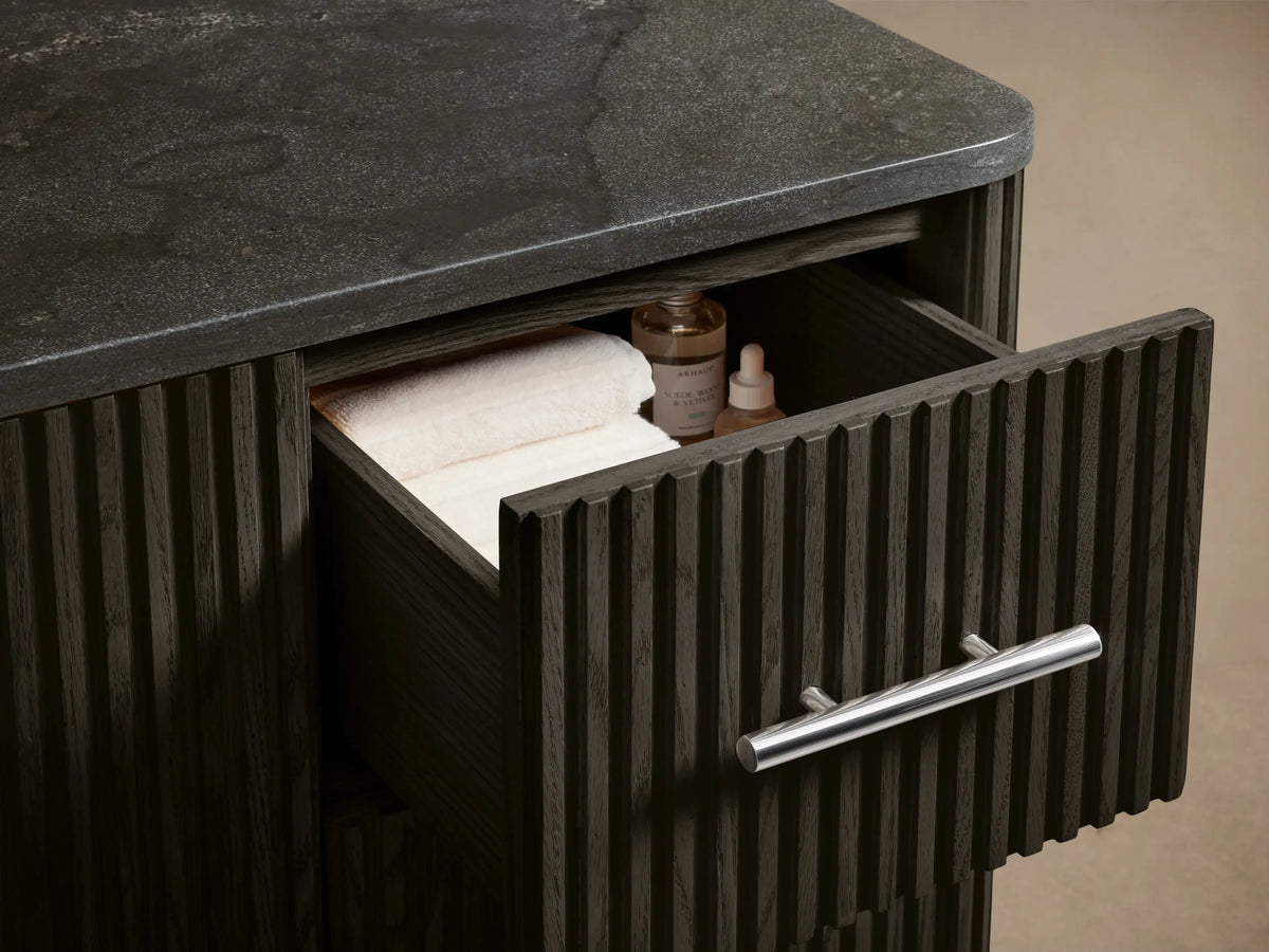 Close-up of Finnley Wide Single Vanity's dark ribbed wood, polished nickel handles. Door slightly open to reveal interior shelf.