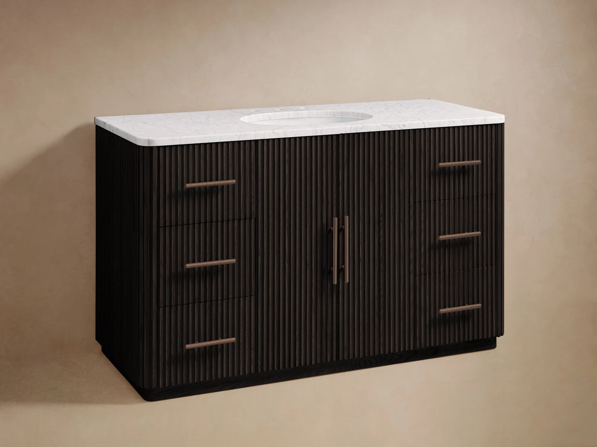 Finnley Wide Single Vanity in dark fluted wood, white marble top, oval sink, bronze faucet, 6 drawers, 2 central doors.