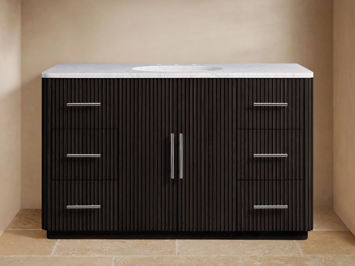 The image shows the Finnley Single Wide Vanity with a dark oak finish. It has a white stone top and an oval ceramic sink, with silver hardware on six drawers and two central doors.