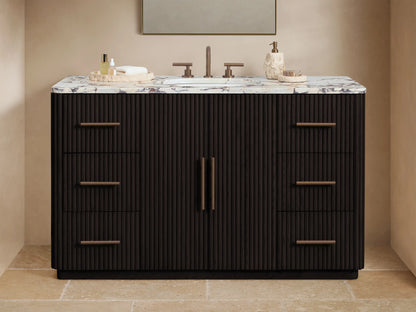 Finnley Wide Single Vanity in dark fluted wood with a white marble top, oval sink, two doors, and six drawers with bronze pull handles.