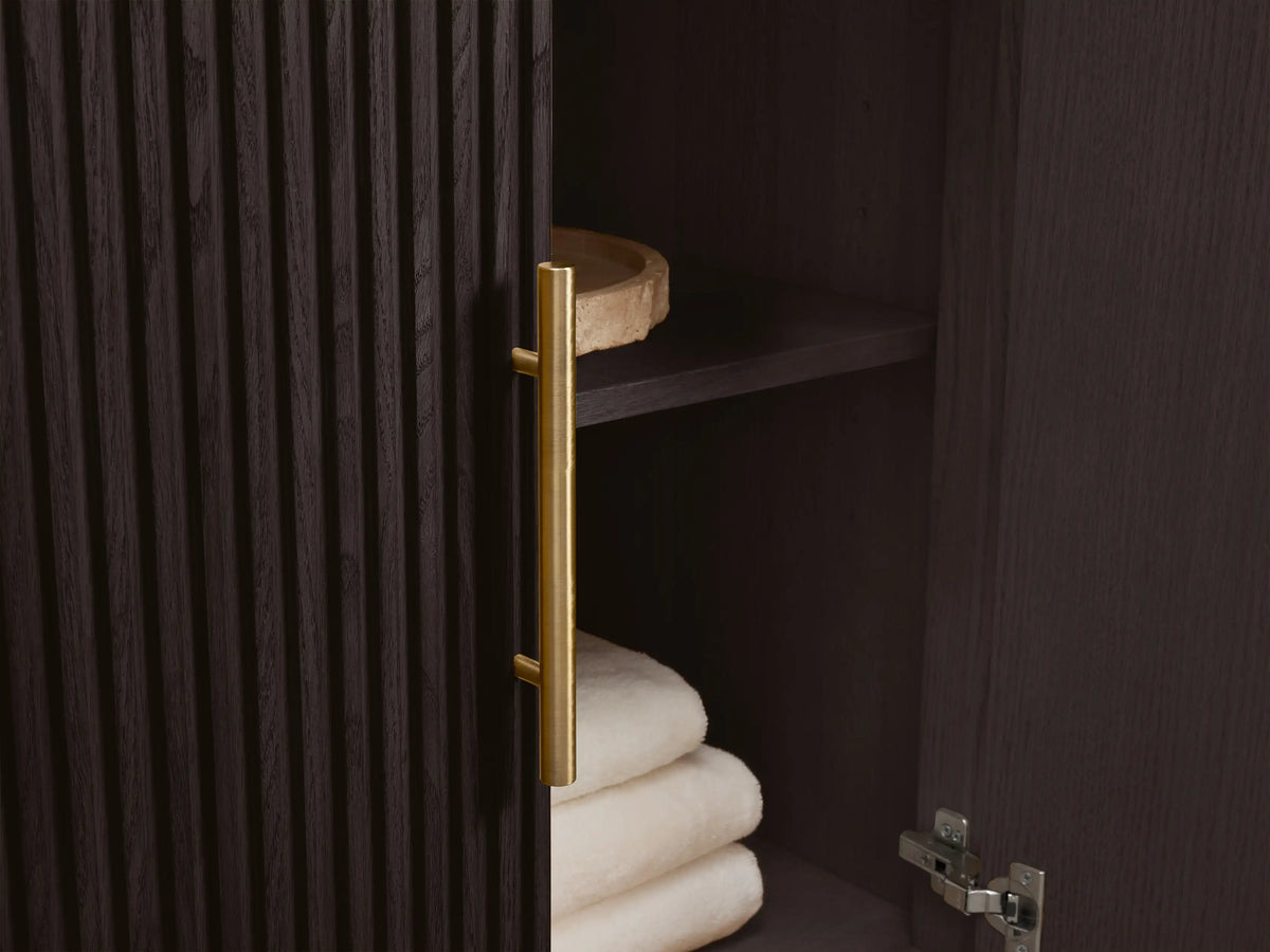 Angled close-up of Finnley Wide Single Vanity. White oval sink in veined marble top with faucet holes. Dark ridged base.