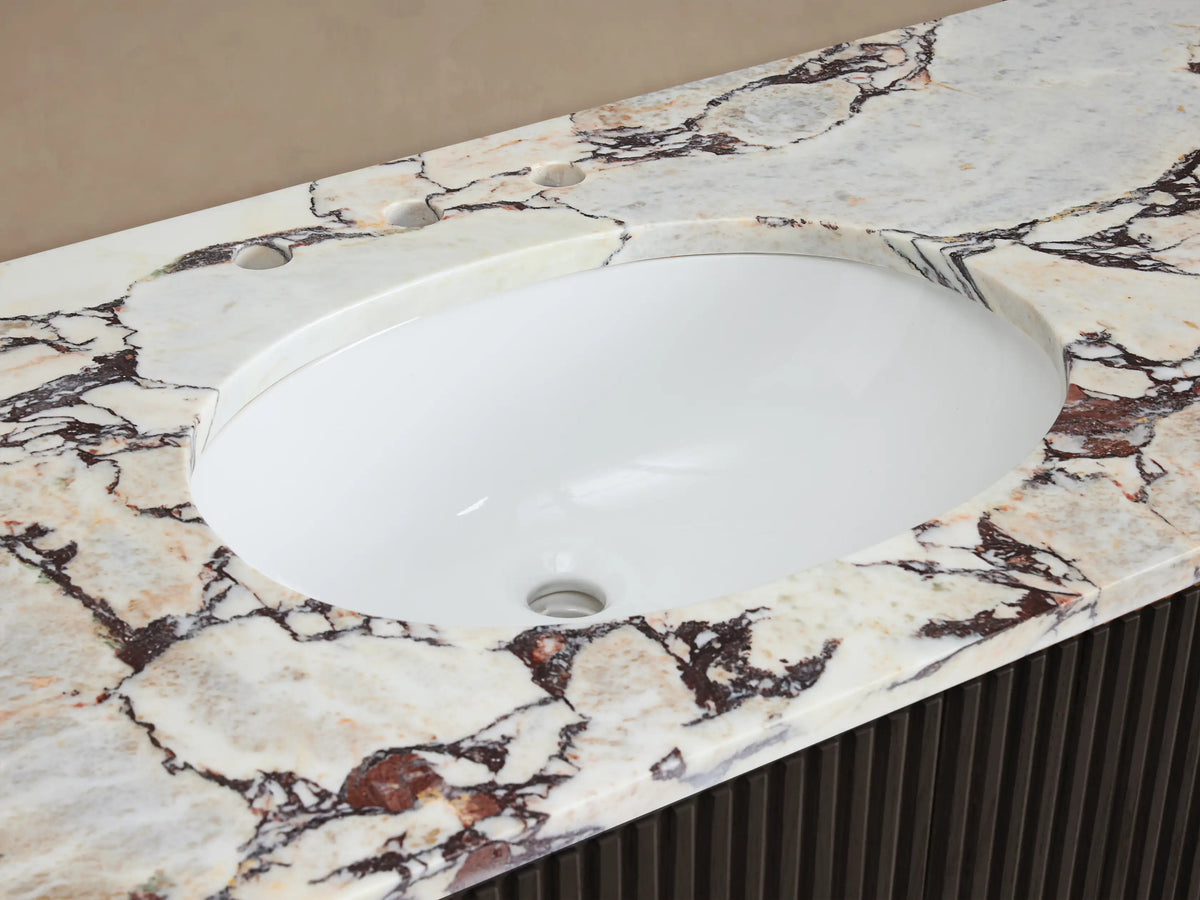Close-up of Finnley Wide Single Vanity: white oval sink, cream marble countertop with reddish-brown veining, chrome faucet.