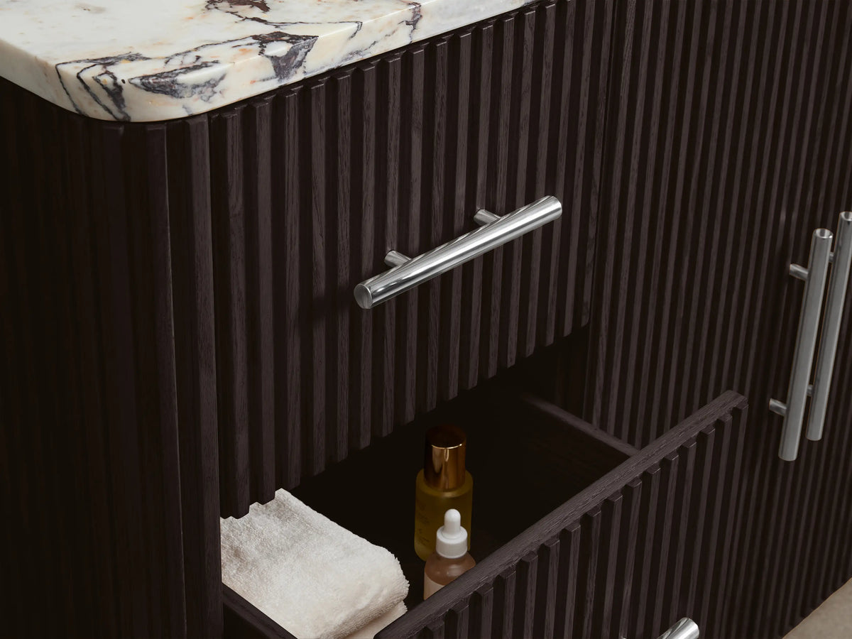 Close-up of Finnley Wide Single Vanity's dark brown fluted cabinet door, polished nickel pull, open to reveal shelves with white towels.