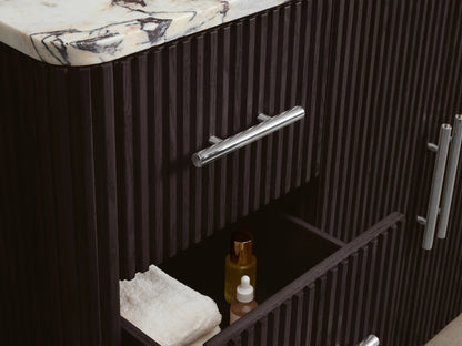 Close-up of Finnley Wide Single Vanity's dark brown fluted cabinet door, polished nickel pull, open to reveal shelves with white towels.