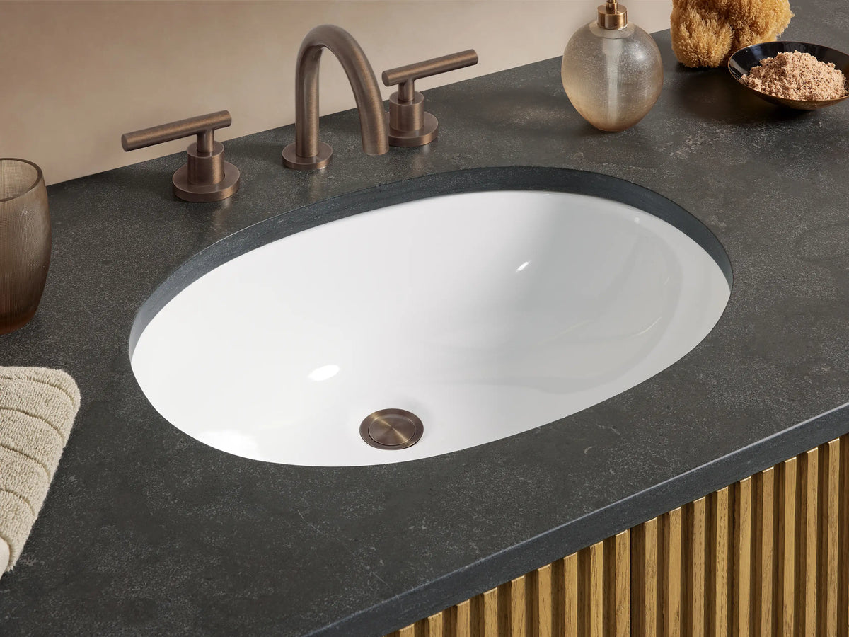 Finnley Wide Single Vanity with fluted light wood, dark stone top, oval sink, 2 central doors & 6 drawers with dark bar pulls.