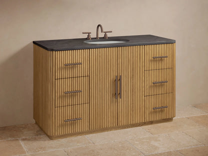 Finnley Wide Single Vanity: Dark gray stone top, natural fluted wood base. Open drawer with white towel, bottles, bronze handle.