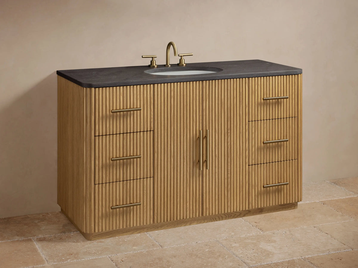 Finnley Single Wide Vanity with open drawer, angled view showing oak wood texture, brass handle, and dark stone top.