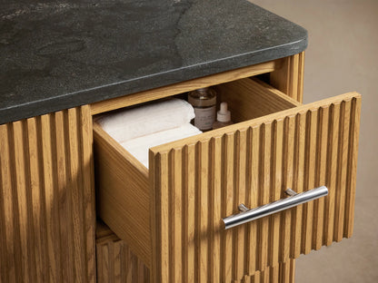 Finnley Single Wide Vanity, oak wood texture with vertical grooves, silver handles, and open door showing shelves with towels.
