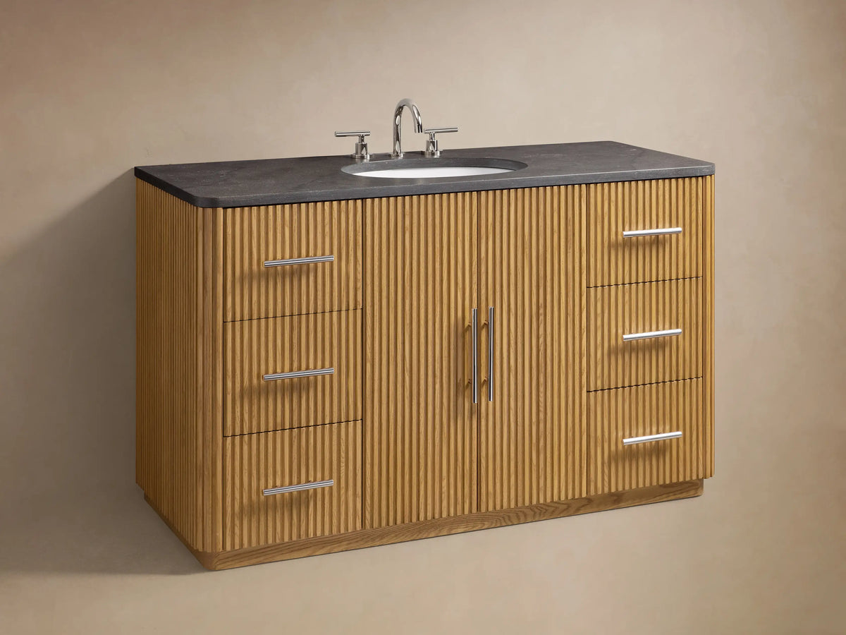 Finnley Single Wide Vanity with ribbed oak wood drawer open, showing towels and bottles; black stone top visible.