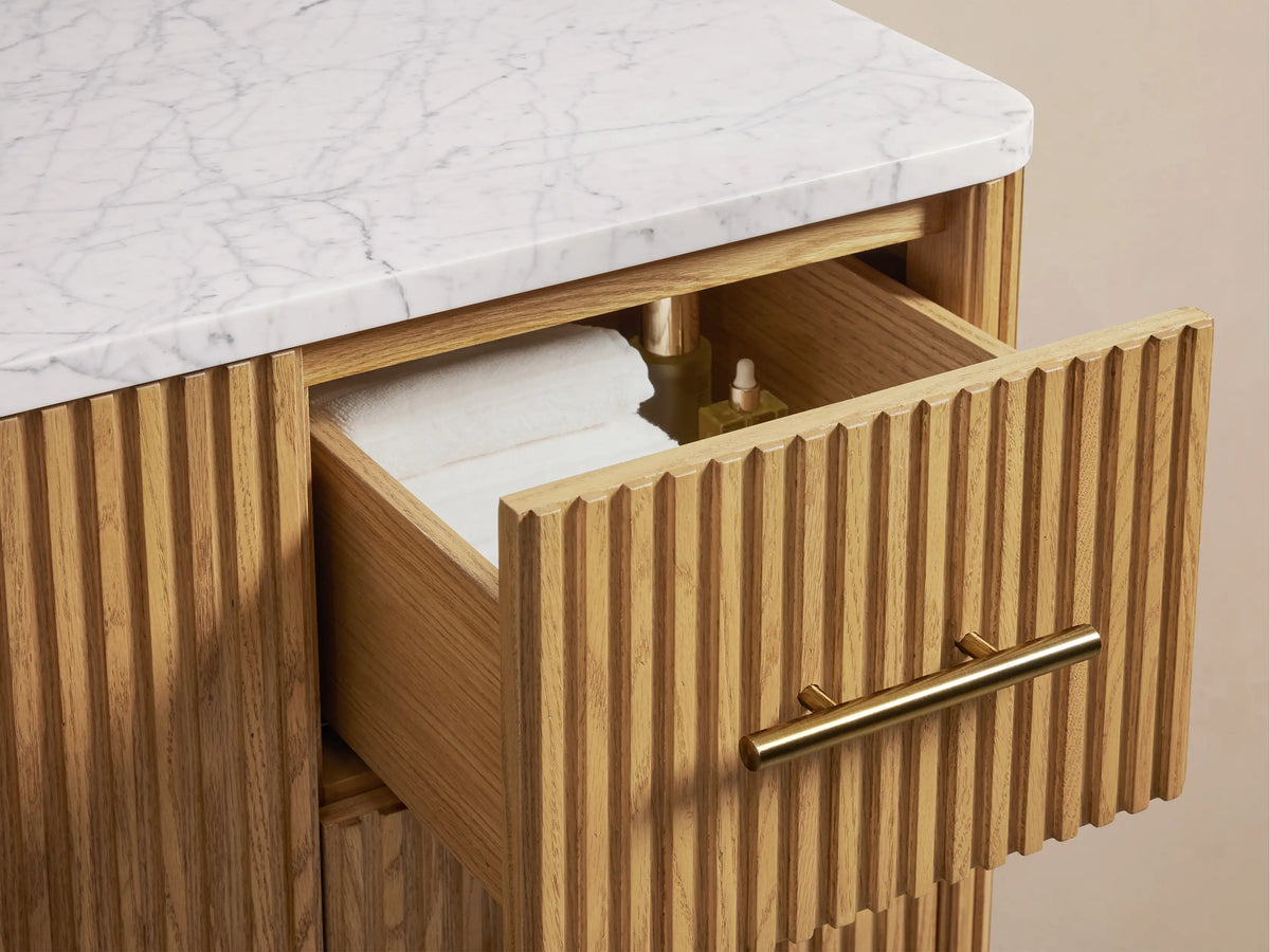 Finnley Single Wide Vanity with a white Carrara marble top, oval ceramic sink, and three pre-drilled holes for faucets.