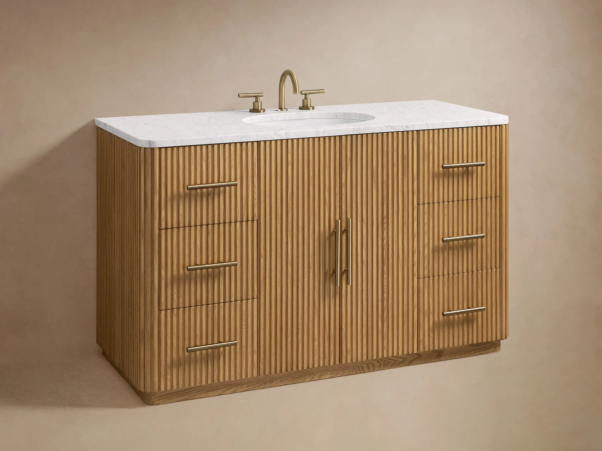 Finnley Single Wide Vanity features ribbed oak wood doors with brass handles, open to show shelves with towels and a box.