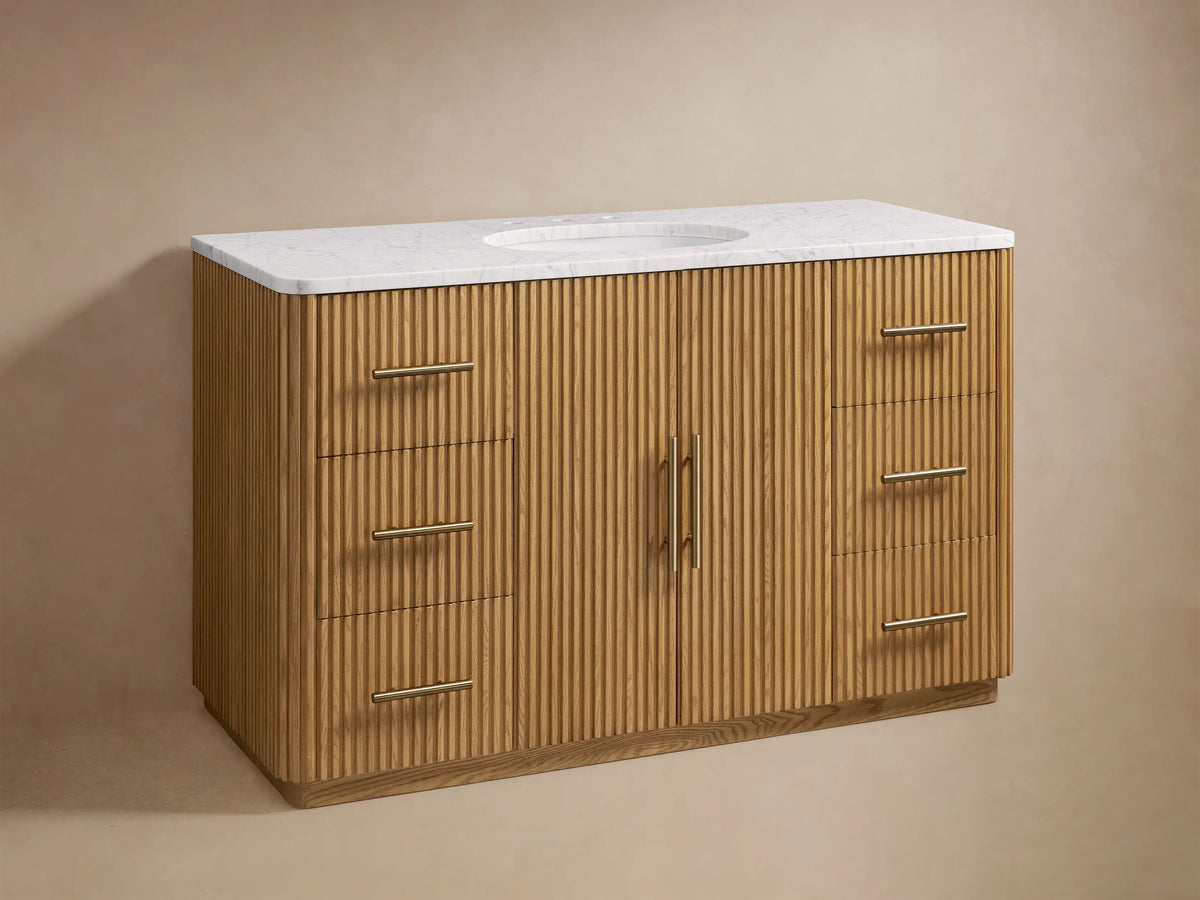 Finnley Single Wide Vanity in oak wood with vertical grooves, white stone top, oval sink, brass hardware, and two side drawers.
