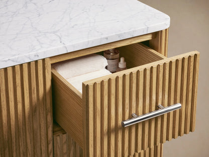 Finnley Single Wide Vanity with a white Carrara marble top, oval ceramic sink, and three faucet holes, on an oak wood base.