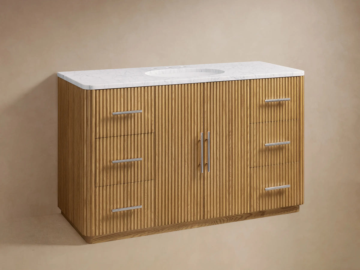 Finnley Single Wide Vanity with ribbed oak wood finish, featuring two central doors and six drawers with polished nickel handles, topped with white marble and a ceramic sink.
