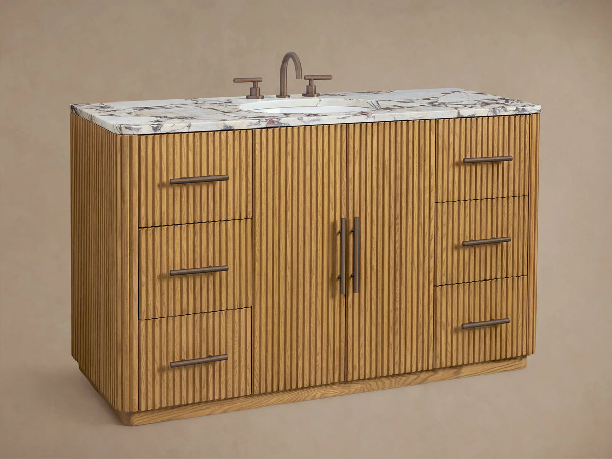 Finnley Wide Single Vanity. Ribbed oak base, white veined marble top with oval sink, & antique bronze pulls.