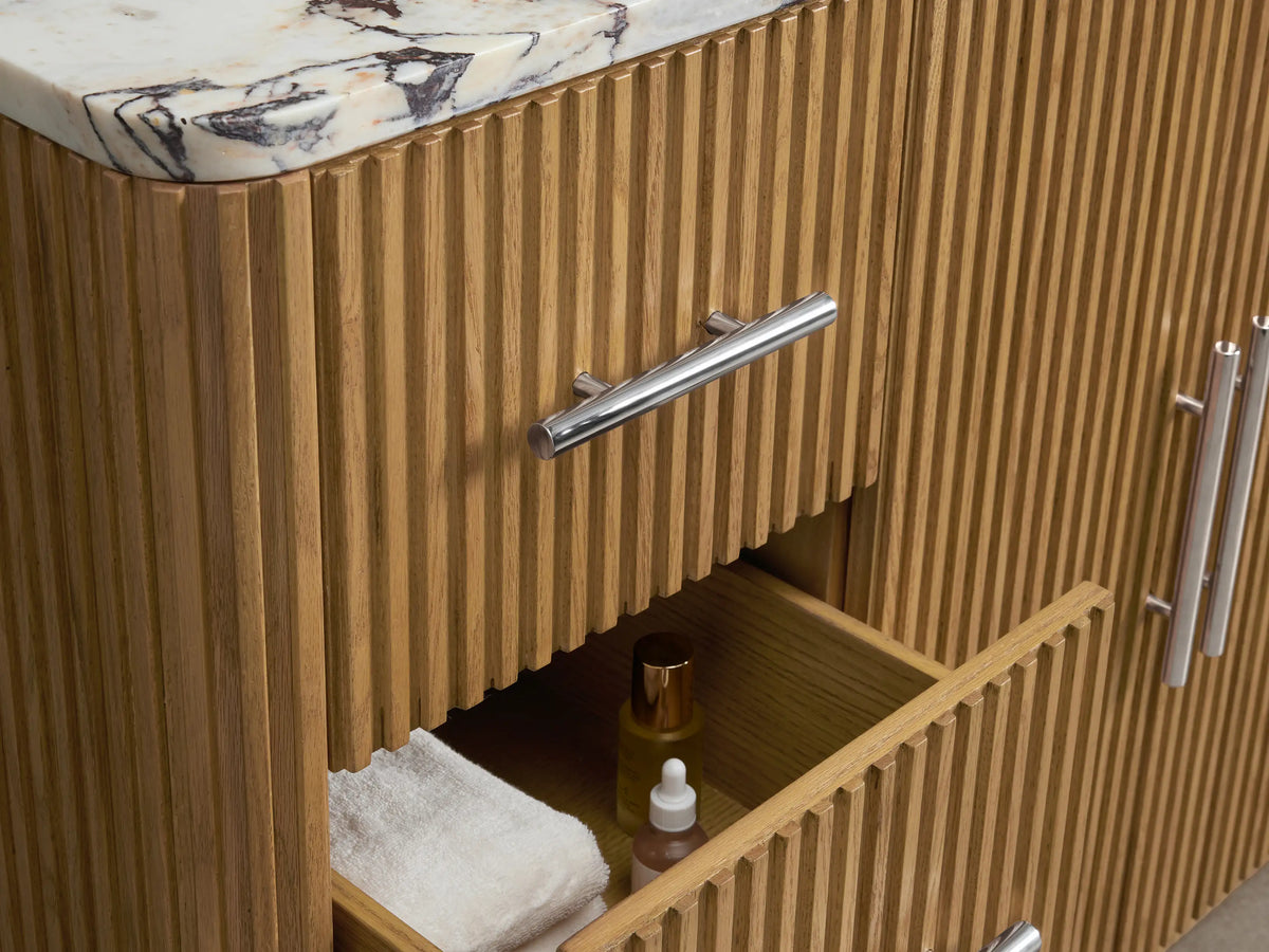 Finnley Wide Single Vanity: Open fluted oak door with polished nickel handle, revealing interior shelf with white towels and stone item.