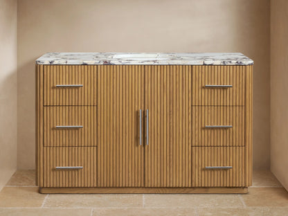 Finnley Wide Single Vanity. Close-up of fluted oak wood, white marble top. Drawer partially open with towel & bottles.