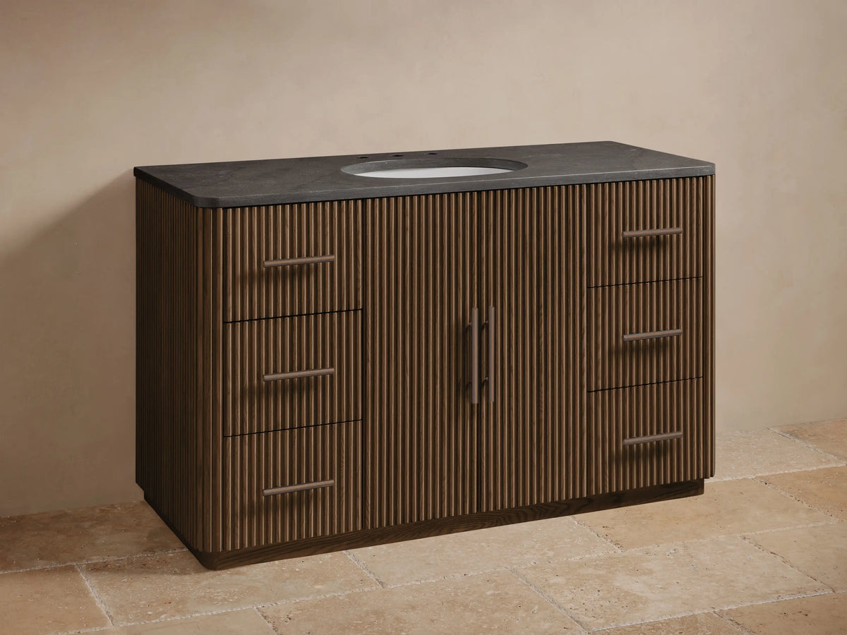 Finnley Wide Single Vanity: Dark brown ribbed wood, dark gray stone top, oval sink, bronze faucet and handles, six drawers.