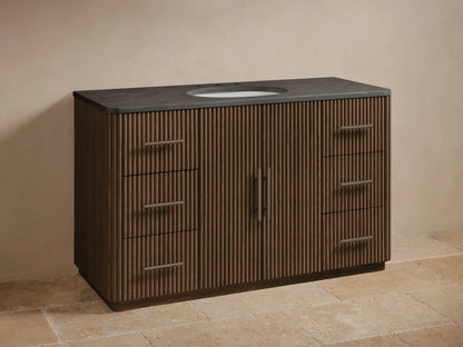 Finnley Wide Single Vanity: Dark brown ribbed wood, dark gray stone top, oval sink, bronze faucet and handles, six drawers.