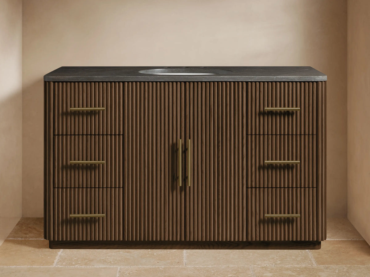 Finnley Wide Single Vanity: dark brown fluted wood, bluestone top, oval sink, brass faucet, 6 side drawers, 2 center doors.