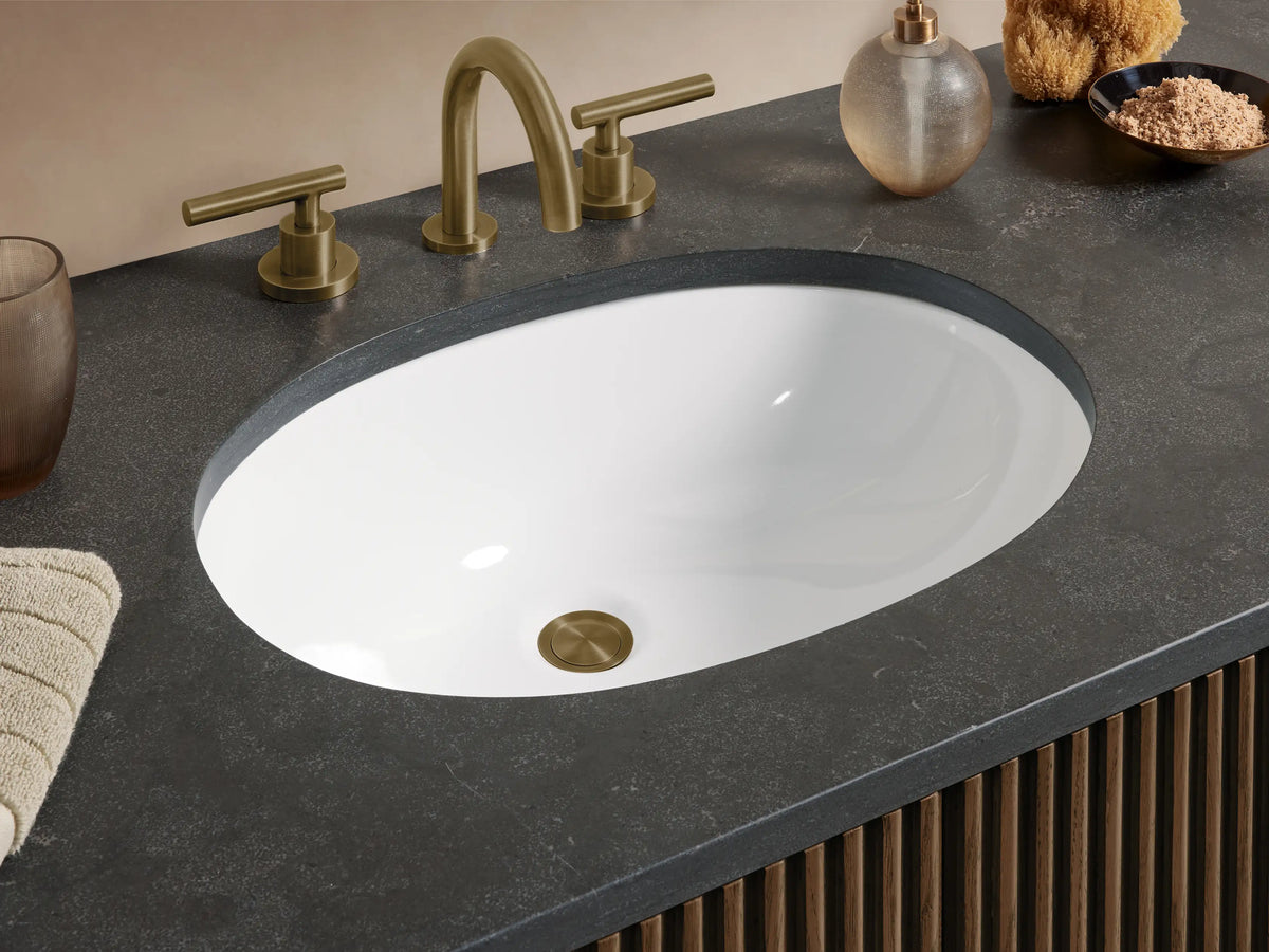 Finnley Wide Single Vanity: Dark brown ribbed wood cabinet, bluestone top, oval sink, 2 doors, 6 drawers with brass pulls.