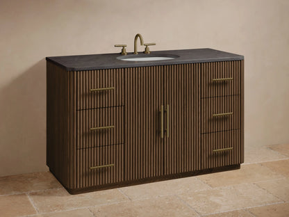 Close-up of Finnley Wide Single Vanity's dark fluted oak door, slightly open, showing white towels & a box. Brass pulls on door & drawers.