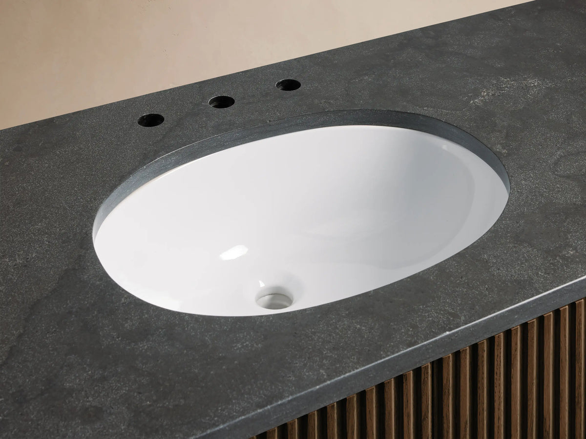 Top-down view of Finnley Wide Single Vanity showing oval white ceramic sink, polished chrome faucet, dark gray stone top & wood base.