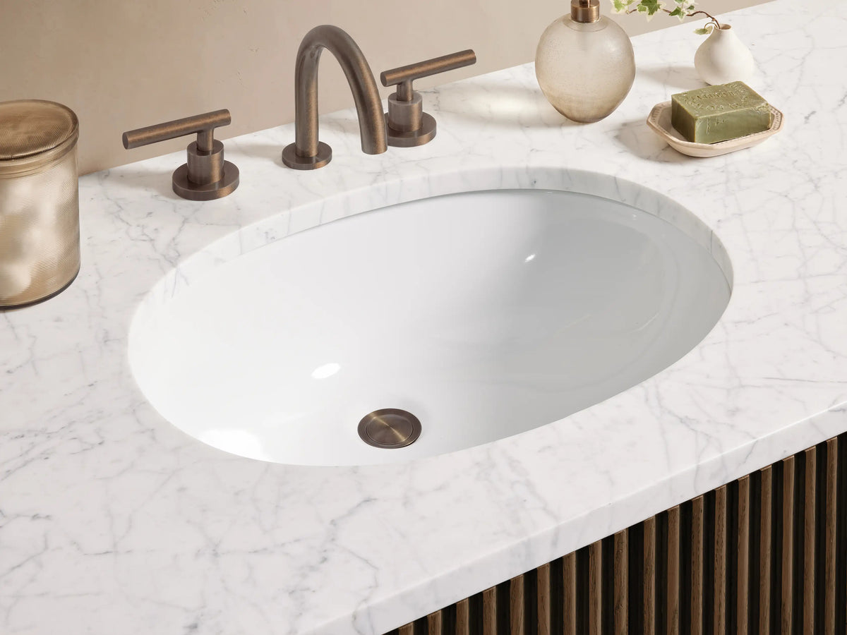 Finnley Wide Single Vanity. Dark brown fluted wood, white marble top with oval sink, 6 drawers, and central doors.