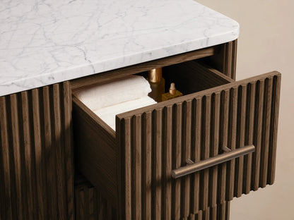 Close-up of Finnley Wide Single Vanity's white Carrara marble top with oval sink & 3 faucet holes. Dark wood base visible.