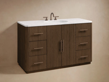 Finnley Wide Single Vanity. Close-up of ribbed dark oak wood. Left door open to shelved interior with box & white towels. Right drawers with bronze-tone pulls.