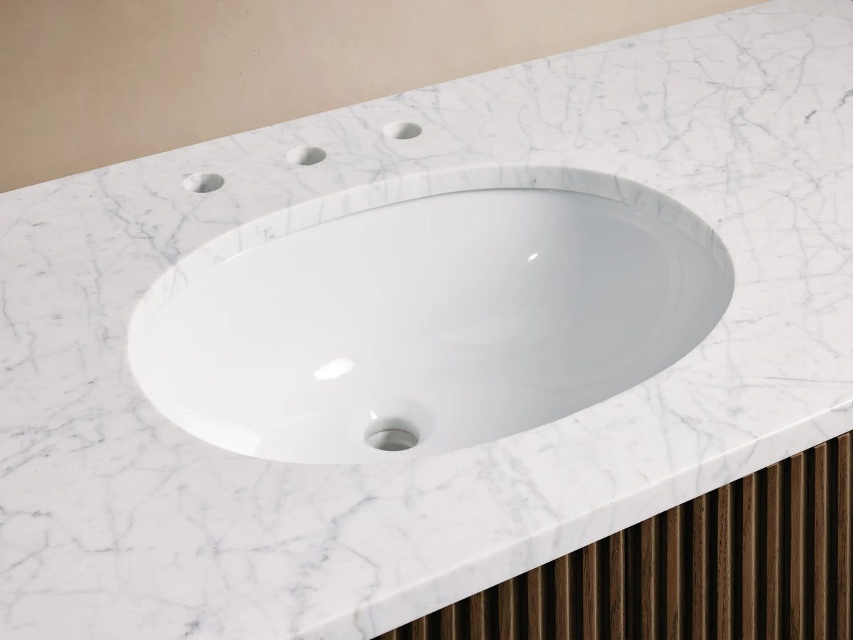 Finnley Wide Single Vanity with oval white sink, white marble countertop, antique bronze faucet, and dark ribbed wood base.