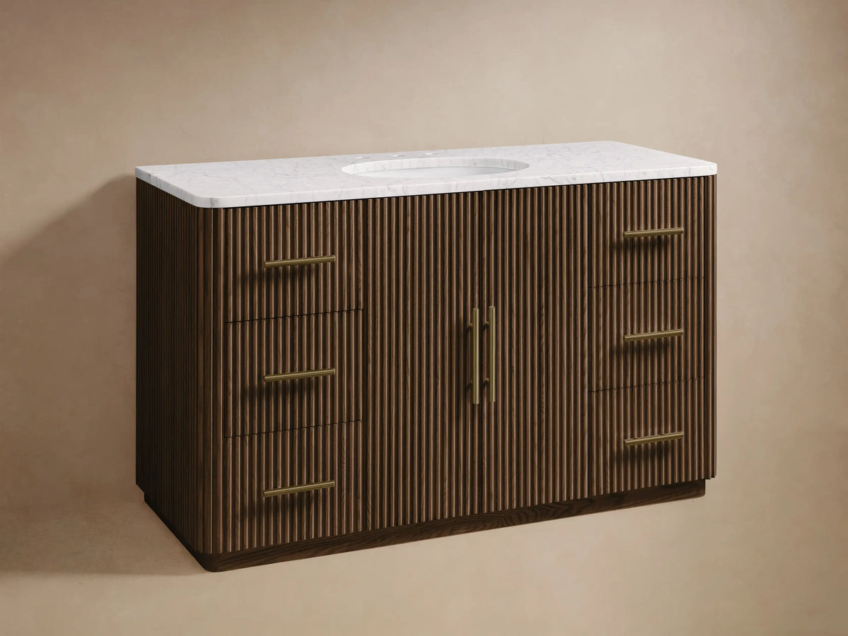 Finnley Wide Single Vanity: Dark brown reeded wood base, white marble top with oval sink, brass faucet, and horizontal handles.
