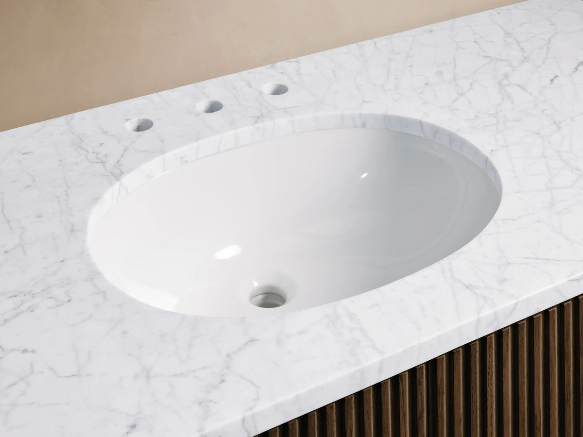 Close-up of Finnley Wide Single Vanity: white oval sink, white Carrara marble top with gray veins, chrome faucet, dark wood base.