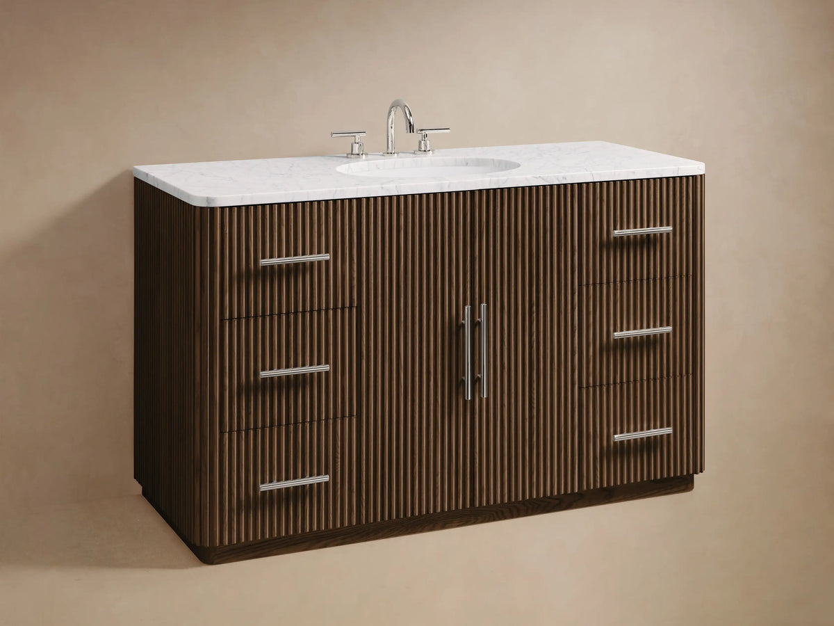 Close-up of Finnley Wide Single Vanity. Dark brown ribbed door slightly ajar, revealing white towels and a box. Polished nickel pulls.