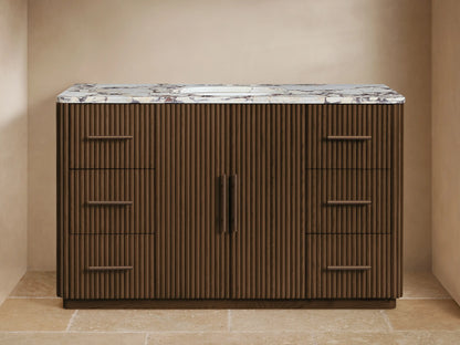 Finnley Wide Single Vanity: Dark fluted wood, white marble top, oval sink, bronze widespread faucet, and pull handles.