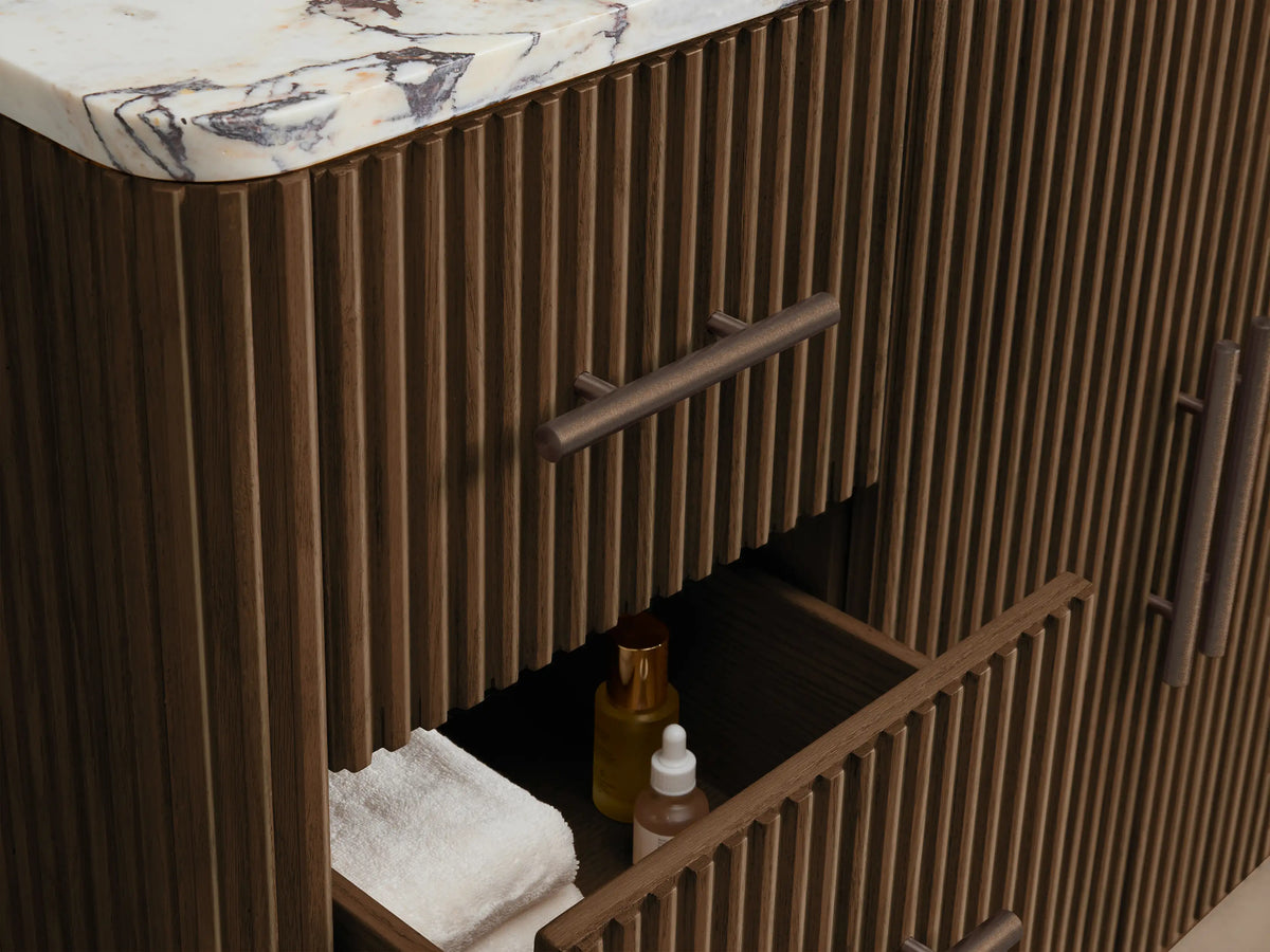 Close-up of Finnley Wide Single Vanity with Calacatta Viola marble top, white oval sink, & 3 faucet holes. Dark ribbed wood base.