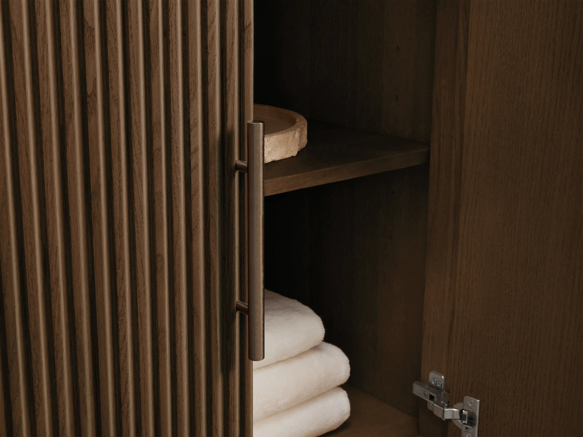 Finnley Single Vanity: white Carrara marble top, fluted dark wood, open drawer showing towels & bottles. Antique bronze pull.